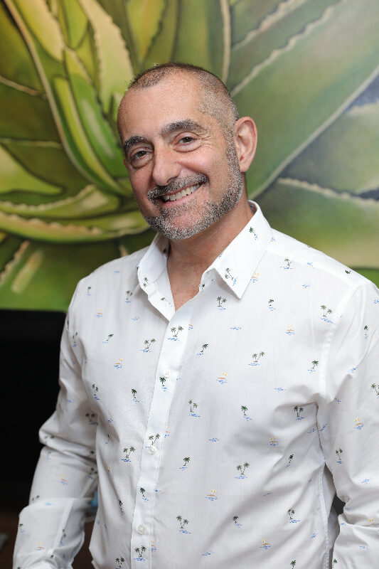 A man with a beard and mustache wearing a white shirt.